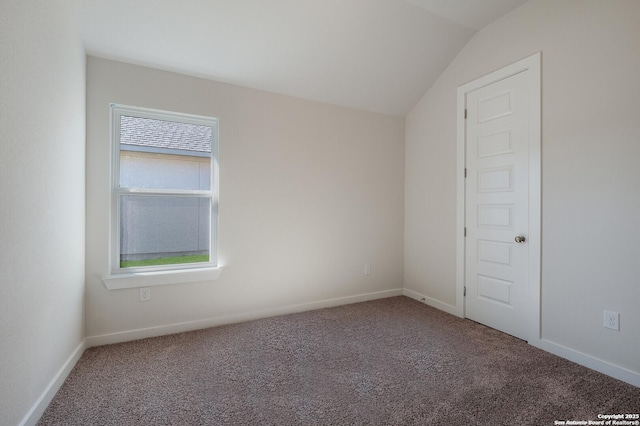 empty room featuring carpet flooring and vaulted ceiling