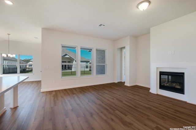 unfurnished living room featuring dark hardwood / wood-style floors and a chandelier