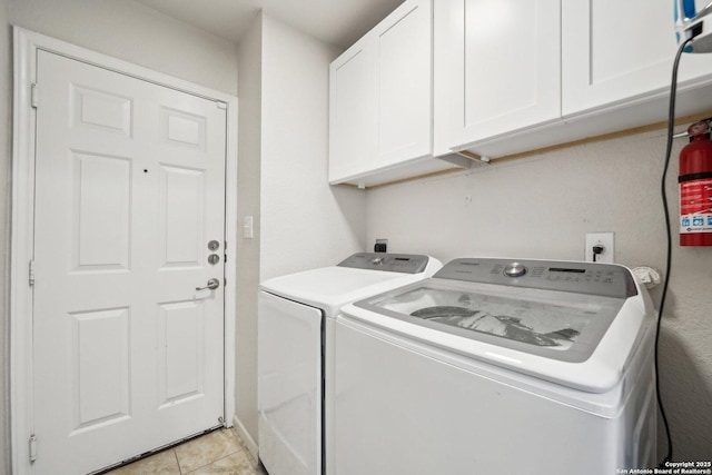 clothes washing area with separate washer and dryer, light tile patterned floors, and cabinets