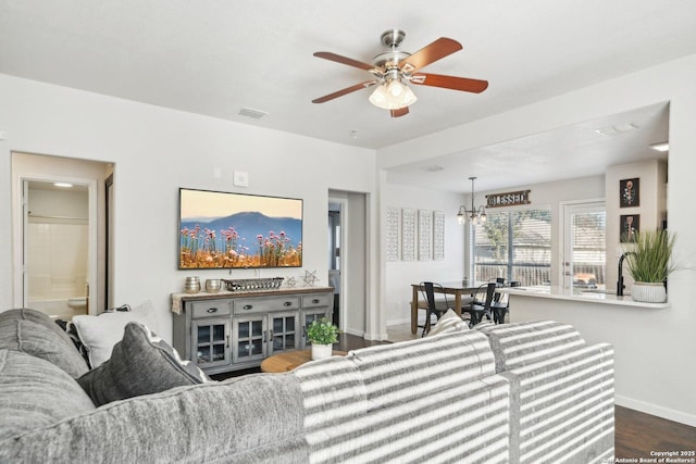 living room featuring ceiling fan with notable chandelier and dark hardwood / wood-style flooring