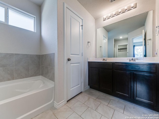 bathroom with a wealth of natural light, tile patterned flooring, vanity, and a bath