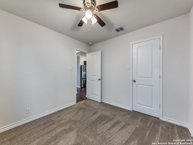 unfurnished bedroom featuring carpet flooring, ceiling fan, and stainless steel fridge