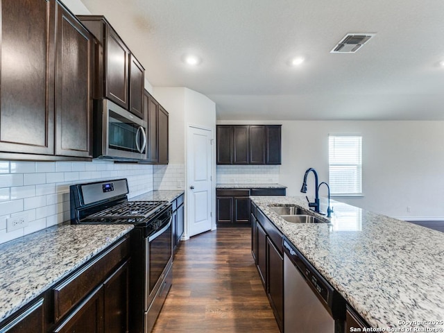 kitchen with light stone countertops, sink, stainless steel appliances, dark hardwood / wood-style floors, and decorative backsplash