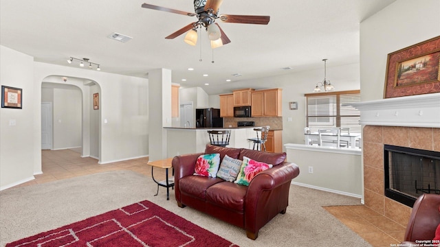 living room featuring ceiling fan, light colored carpet, and a fireplace