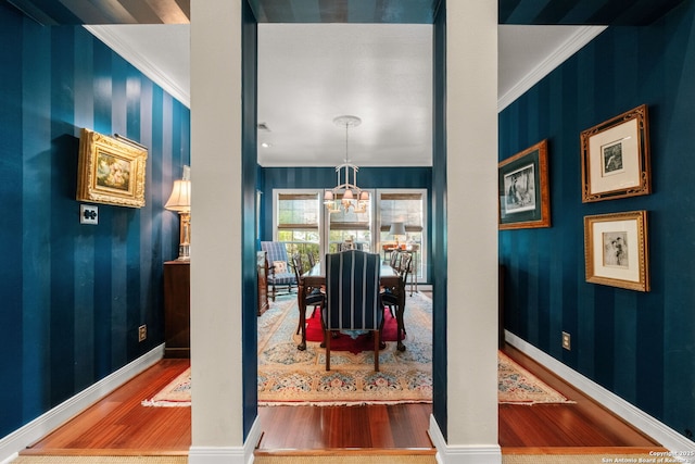 dining area featuring crown molding, wood-type flooring, and an inviting chandelier