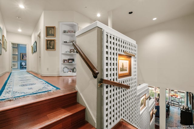 staircase with built in shelves and wood-type flooring