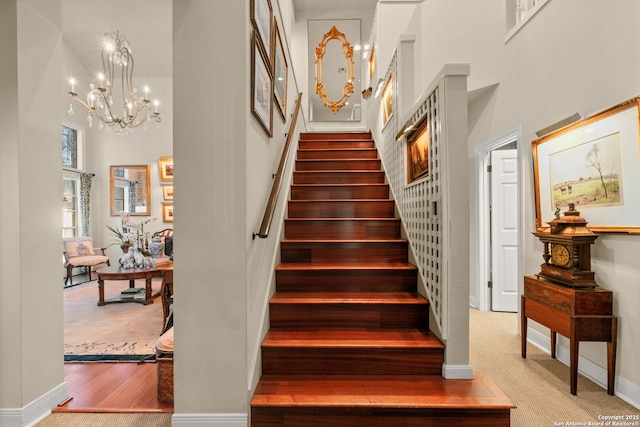 stairway featuring carpet flooring, a towering ceiling, and a chandelier