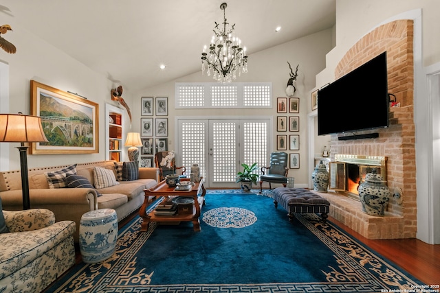 living room featuring hardwood / wood-style flooring, a fireplace, high vaulted ceiling, and a chandelier