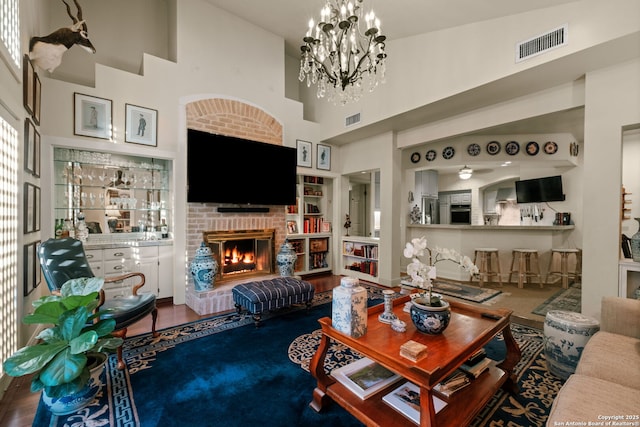 living room with a fireplace, a high ceiling, and an inviting chandelier