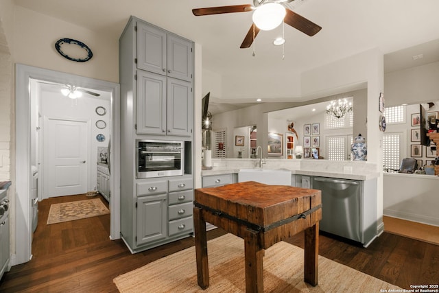 kitchen featuring ceiling fan with notable chandelier, sink, dark hardwood / wood-style flooring, kitchen peninsula, and stainless steel appliances