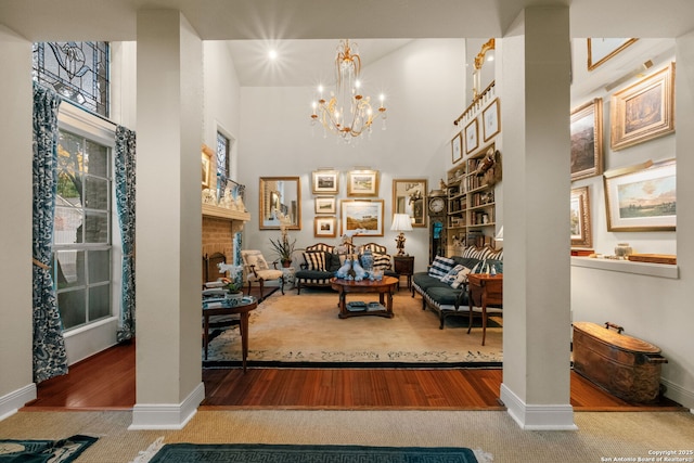 living area with carpet flooring, ornate columns, and a notable chandelier