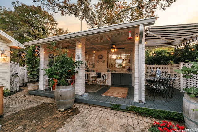 patio terrace at dusk featuring a deck and ceiling fan