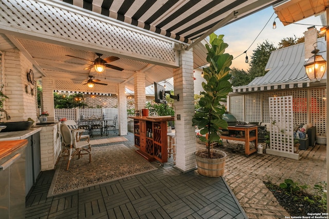 patio terrace at dusk featuring ceiling fan and a bar