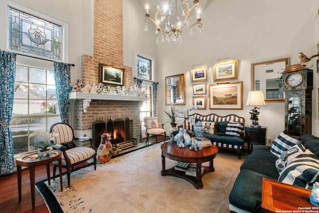 living room with hardwood / wood-style flooring, a towering ceiling, a fireplace, and a chandelier