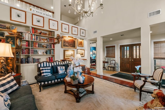 living room featuring light hardwood / wood-style floors, a towering ceiling, and a chandelier