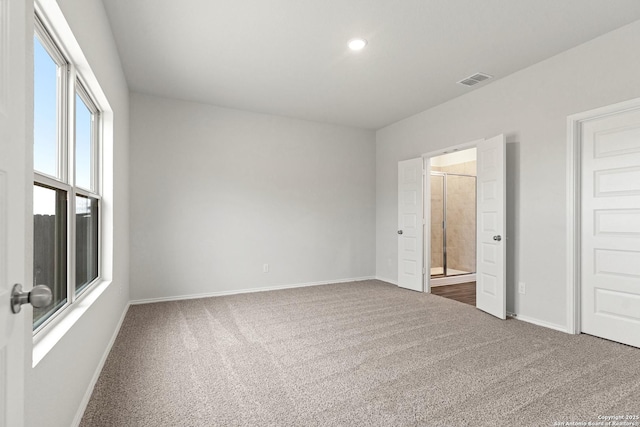 unfurnished bedroom with dark colored carpet and ensuite bathroom