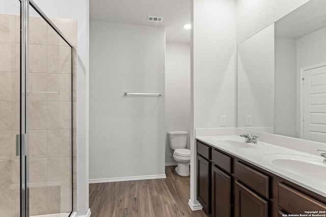 bathroom featuring walk in shower, hardwood / wood-style flooring, vanity, and toilet