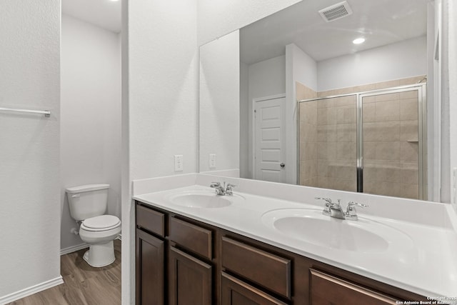 bathroom featuring vanity, wood-type flooring, a shower with shower door, and toilet