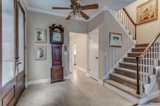 foyer featuring ceiling fan, light tile patterned floors, a textured ceiling, and ornamental molding