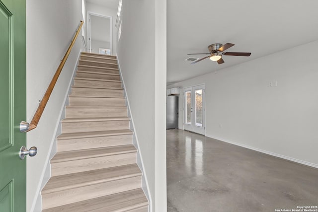 staircase featuring ceiling fan, french doors, and concrete floors