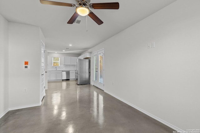 unfurnished living room featuring ceiling fan and concrete flooring