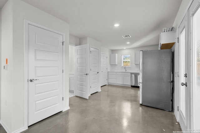 kitchen with appliances with stainless steel finishes, white cabinetry, and sink