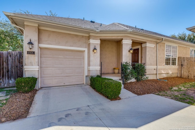 ranch-style home featuring stucco siding, an attached garage, roof with shingles, and fence