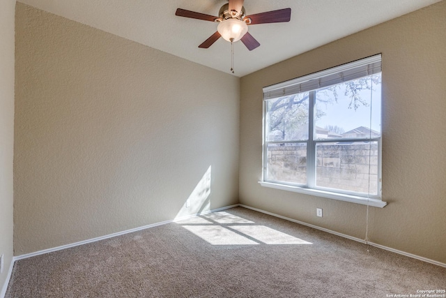 carpeted spare room featuring a ceiling fan, a textured wall, and baseboards