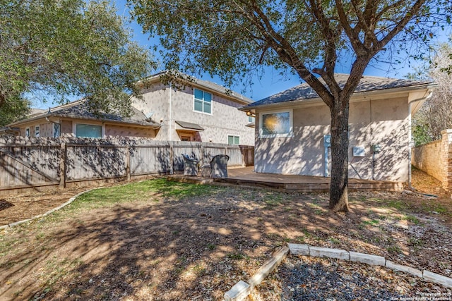 rear view of house featuring stucco siding, a wooden deck, and a fenced backyard