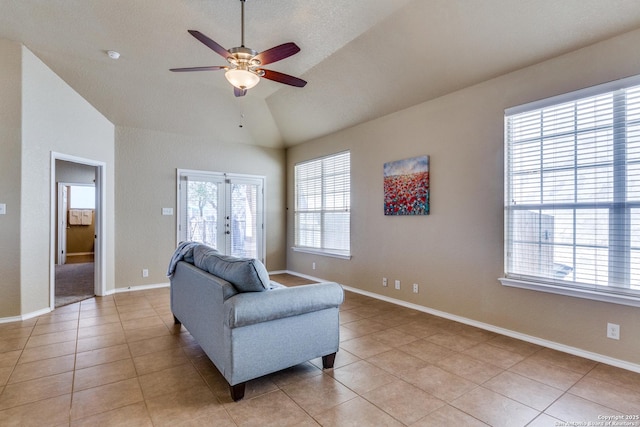 living area featuring lofted ceiling, light tile patterned floors, a ceiling fan, and baseboards