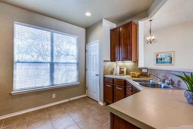 kitchen with a sink, backsplash, light countertops, light tile patterned floors, and baseboards