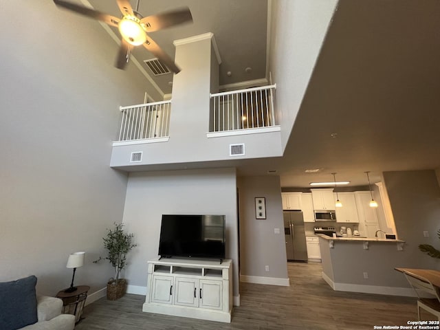 living room featuring ceiling fan, wood-type flooring, and a towering ceiling