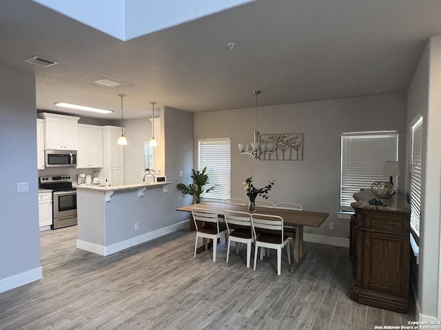 dining area featuring light hardwood / wood-style floors and an inviting chandelier