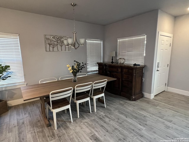 dining area with light wood-type flooring and an inviting chandelier