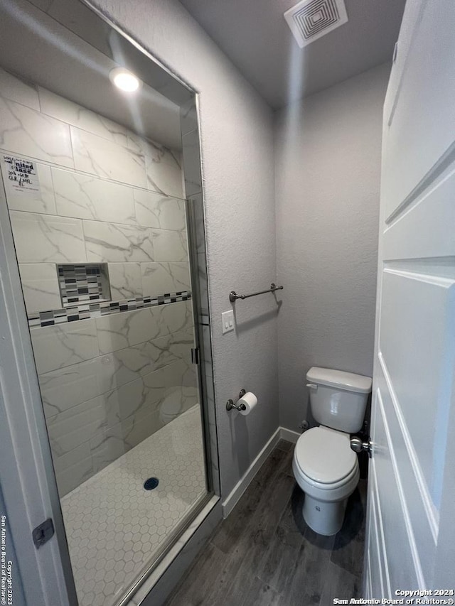 bathroom with hardwood / wood-style flooring, toilet, and an enclosed shower