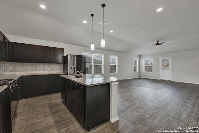 kitchen with vaulted ceiling, ceiling fan, black appliances, a center island with sink, and hanging light fixtures