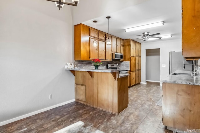 kitchen with a kitchen breakfast bar, sink, decorative light fixtures, kitchen peninsula, and stainless steel appliances