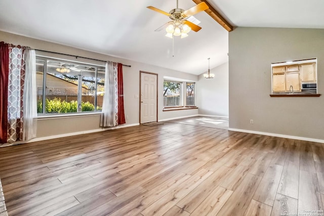 unfurnished living room featuring vaulted ceiling with beams, sink, light hardwood / wood-style floors, and ceiling fan with notable chandelier