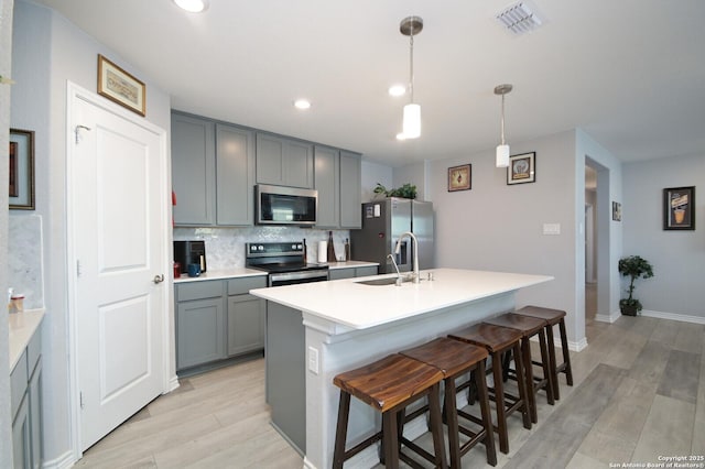 kitchen with sink, tasteful backsplash, pendant lighting, a kitchen bar, and appliances with stainless steel finishes