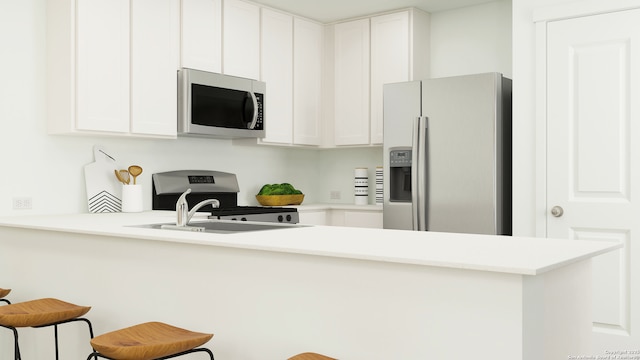 kitchen featuring kitchen peninsula, appliances with stainless steel finishes, sink, white cabinets, and a breakfast bar area