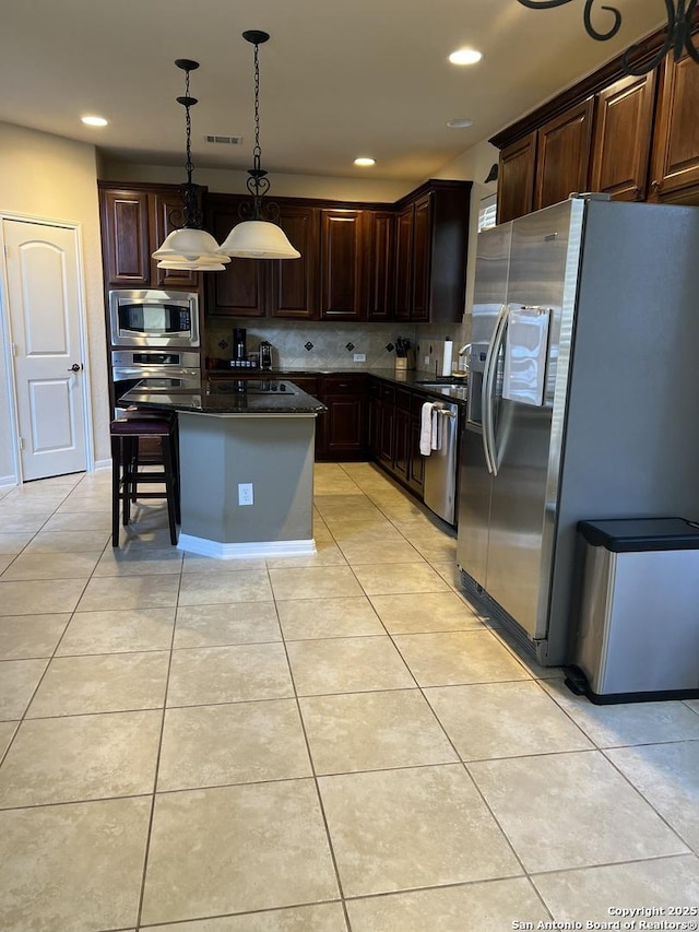 kitchen with light tile patterned flooring, pendant lighting, stainless steel appliances, and a center island