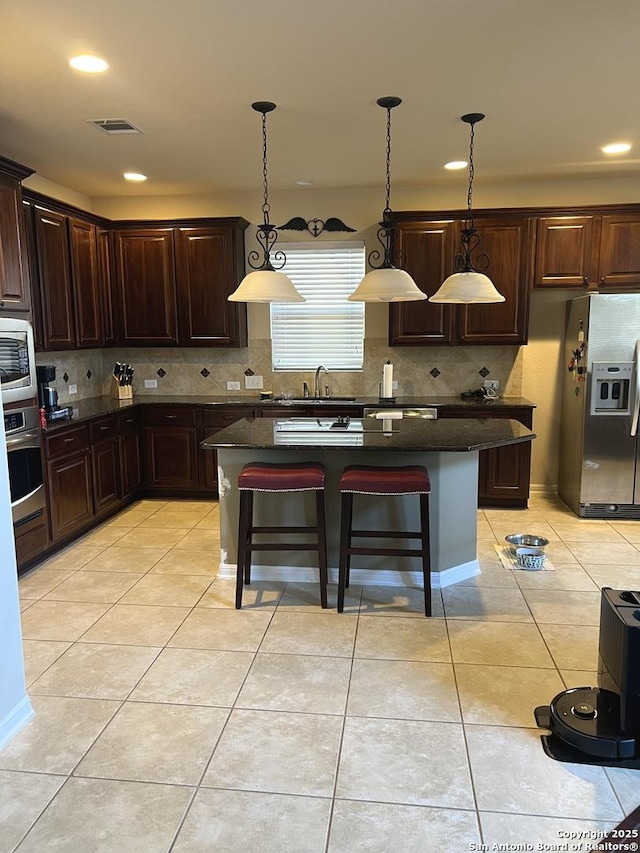 kitchen featuring appliances with stainless steel finishes, decorative light fixtures, and a center island