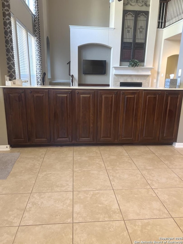 kitchen with light tile patterned flooring, dark brown cabinets, and a tiled fireplace