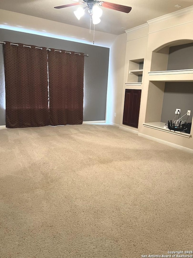 unfurnished living room with ceiling fan, built in shelves, crown molding, and carpet