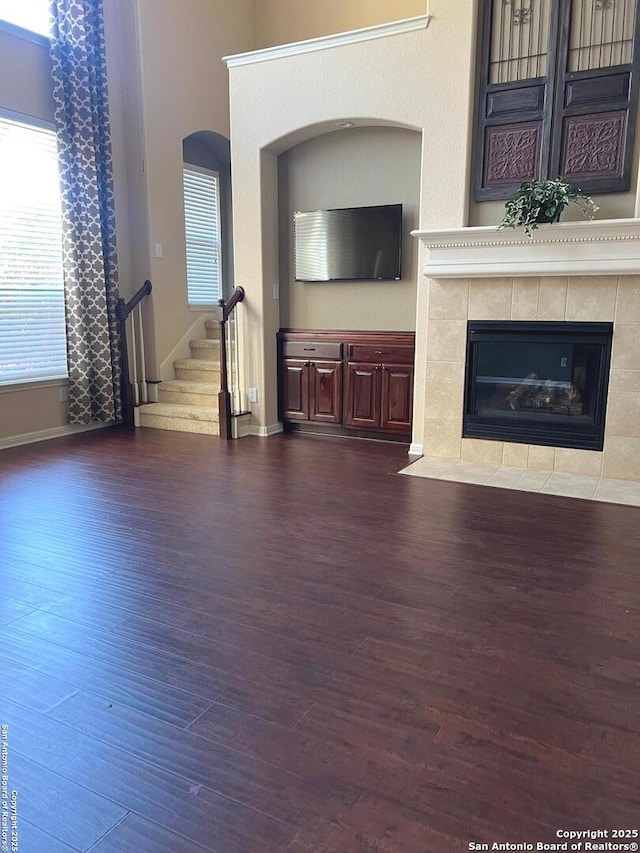 unfurnished living room featuring a tile fireplace and dark hardwood / wood-style flooring