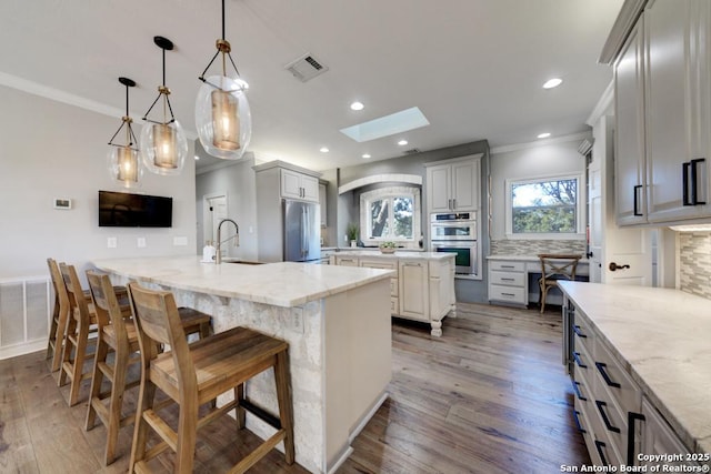 kitchen with a spacious island, a kitchen bar, tasteful backsplash, pendant lighting, and stainless steel appliances