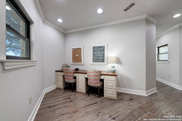 office space with built in desk, ornamental molding, and wood-type flooring