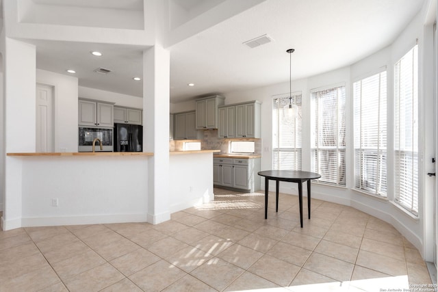 kitchen with kitchen peninsula, tasteful backsplash, black appliances, light tile patterned floors, and gray cabinets