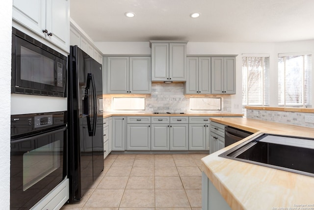 kitchen with wood counters, backsplash, gray cabinetry, and black appliances