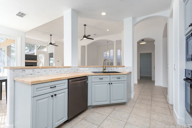 kitchen featuring ceiling fan, sink, wooden counters, decorative backsplash, and appliances with stainless steel finishes